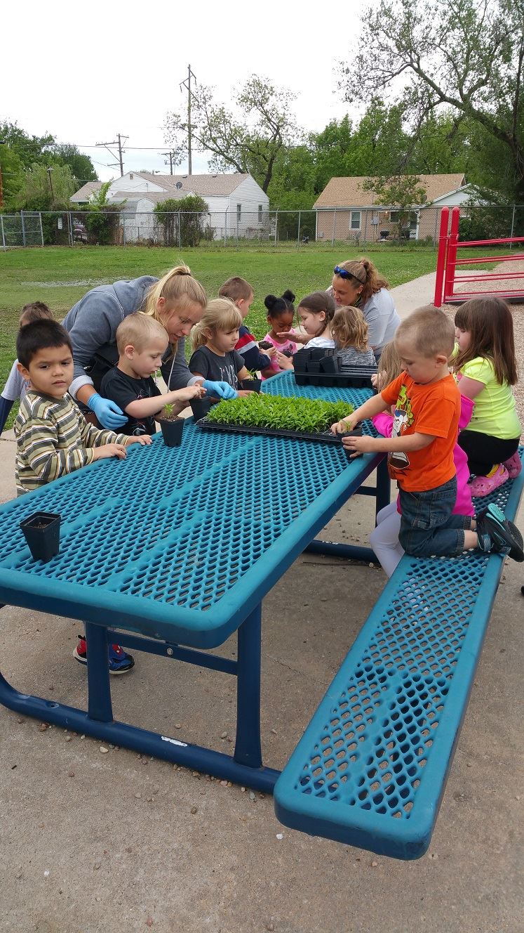 Kids sitting at a picnic table working with plants.